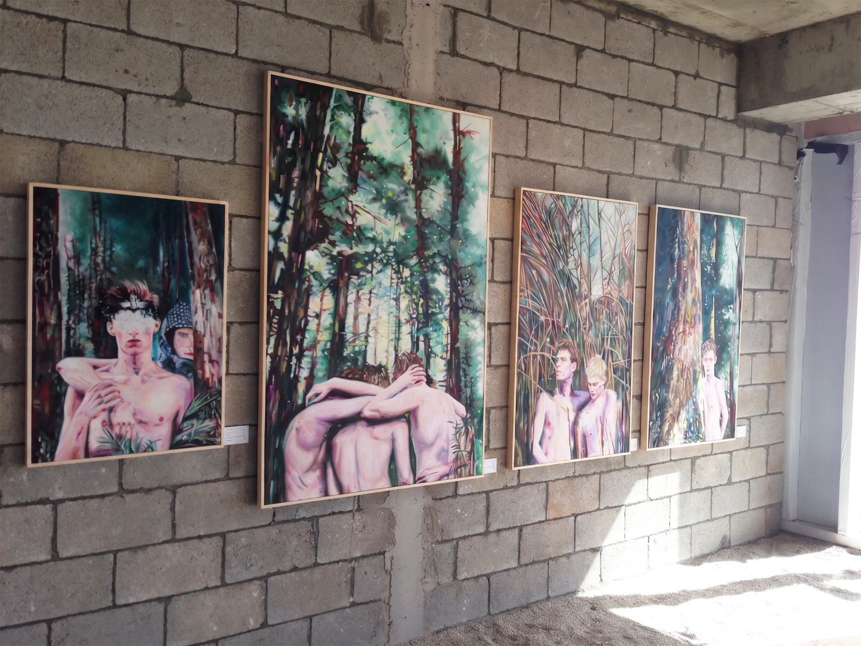Installation view of forest paintings displayed on a white gallery wall.