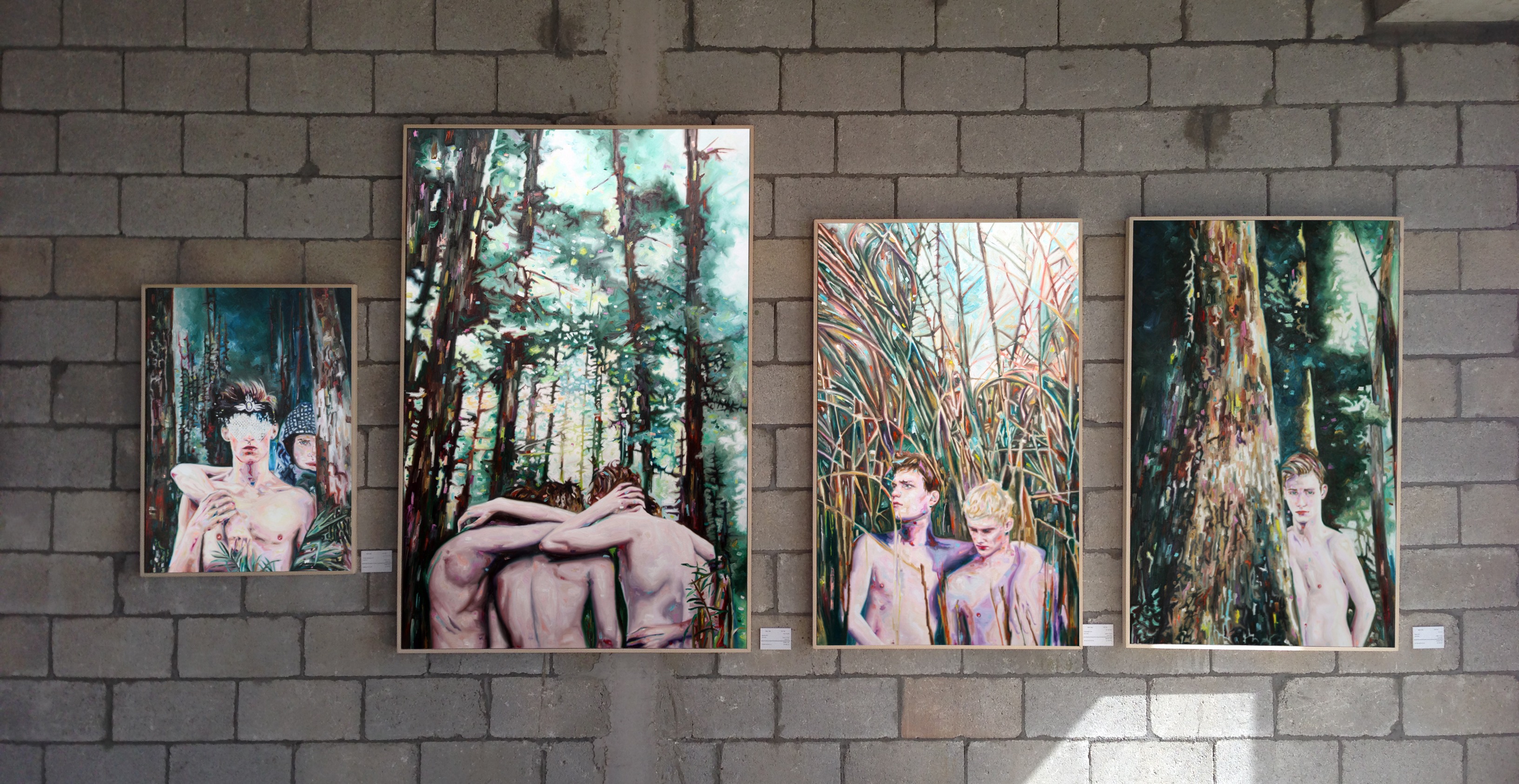 Wide installation view of five forest paintings displayed on an exposed block wall.