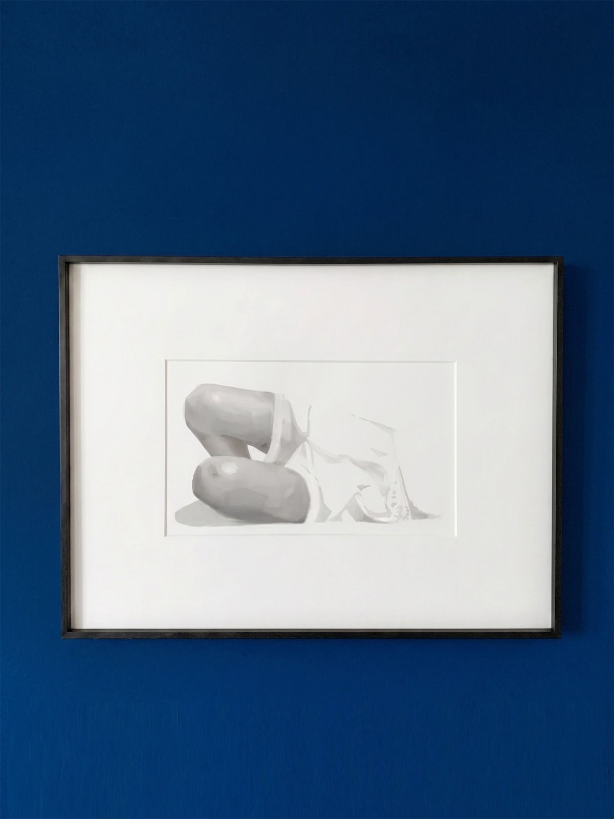 A monochromatic study of a curled figure displayed on a blue wall.