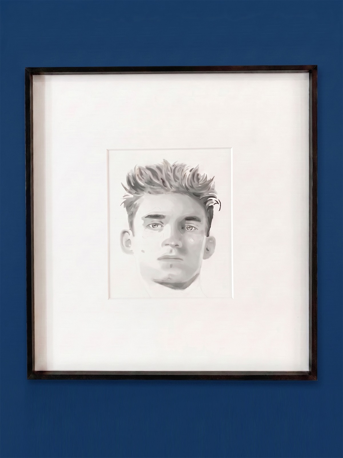 A monochromatic portrait displayed on a blue wall.