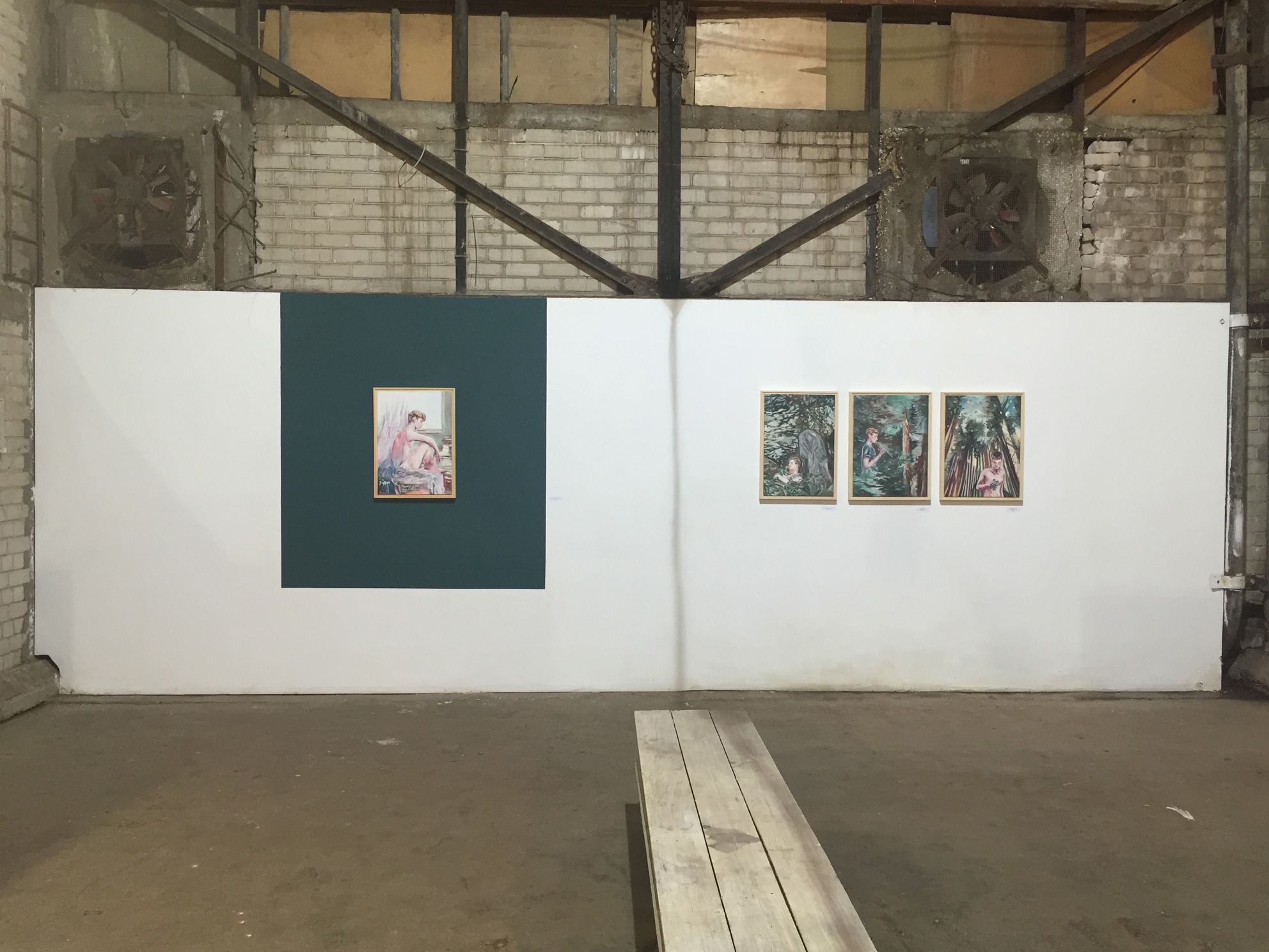 Frontal installation view of four paintings displayed against white and dark teal wall sections.