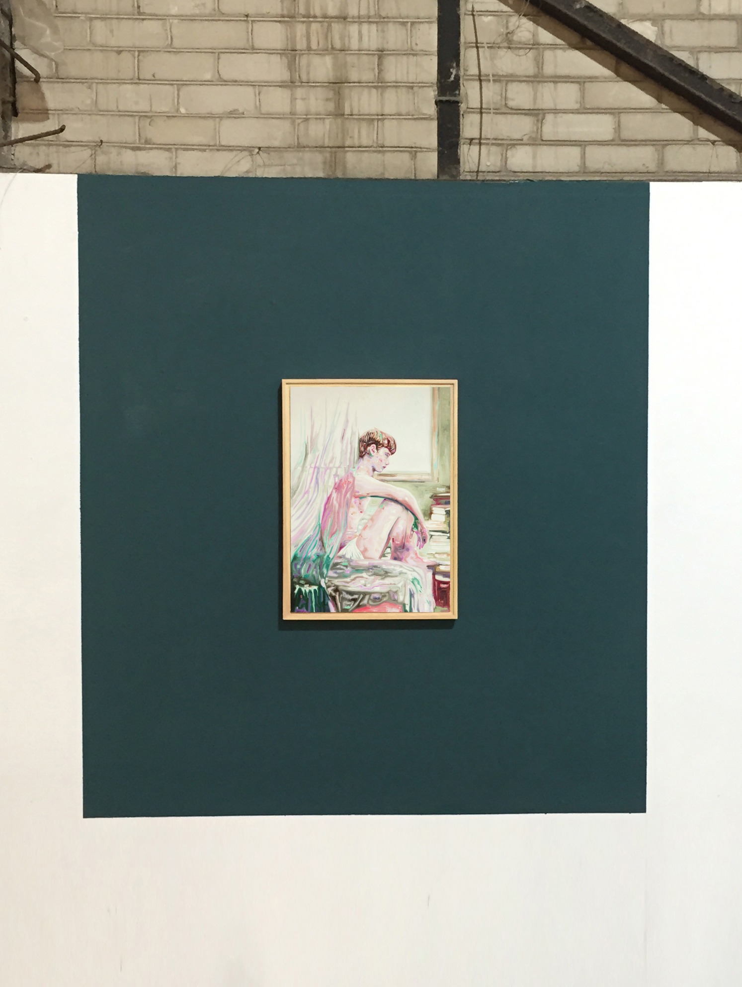 Installation detail of a single painting centered on a dark teal wall panel.