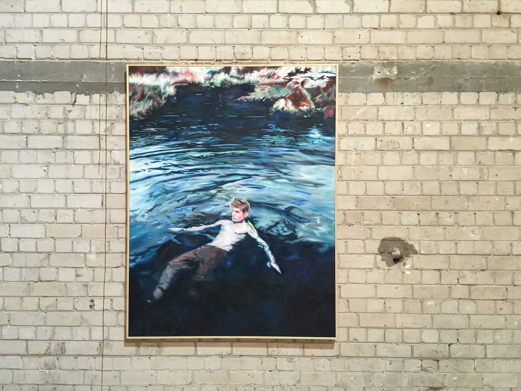 Installation detail of a large swimmer painting mounted on an exposed brick wall.