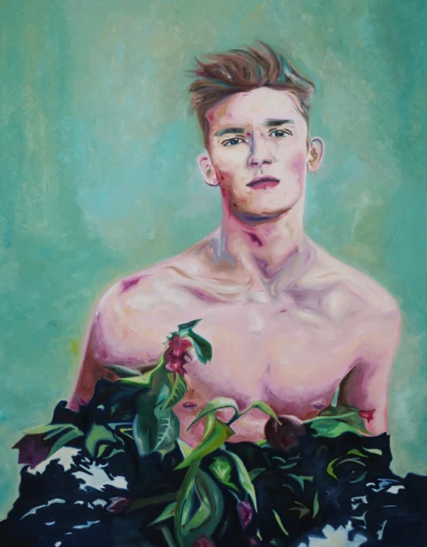 Bare-chested young man standing behind dark leafy plants against a turquoise background.