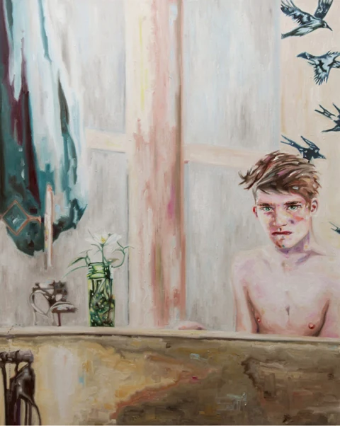 Bare-chested young man seen through a window in a light-filled interior.