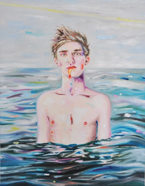 Bare-chested young man standing chest-deep in blue water.