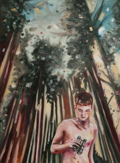 Bare-chested young man standing among tall dark trees.