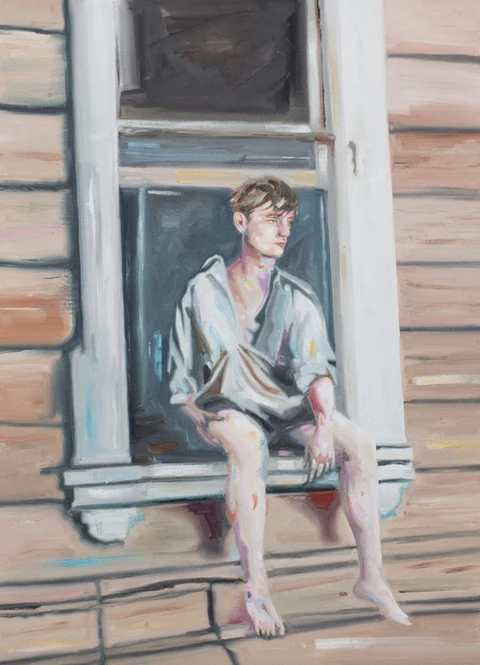 Young man seated in an open window of a wooden house.