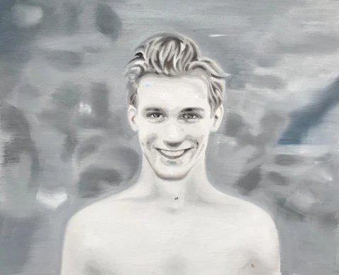 Black-and-white portrait of a smiling bare-chested young man.
