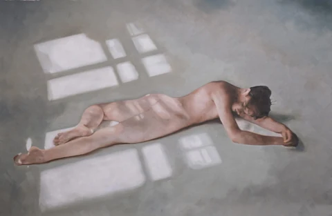 Nude figure lying on a gray floor crossed by window light.