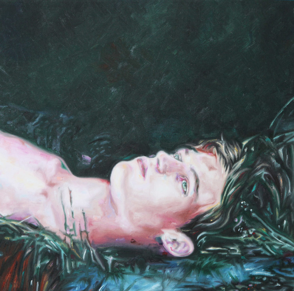 Young man lying on dark grass, shown in profile from close range.
