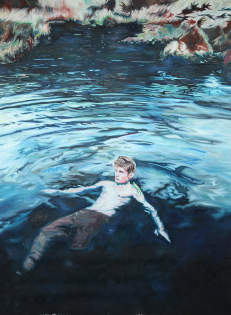 Lone swimmer floating in dark blue water near a rocky shore.