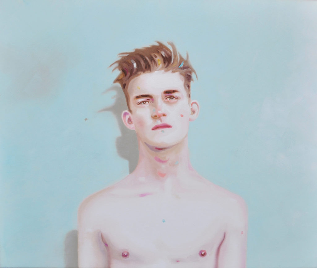 Bare-chested young man facing forward against a pale blue background.