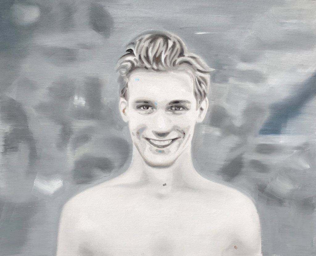 Black-and-white portrait of a smiling bare-chested young man.