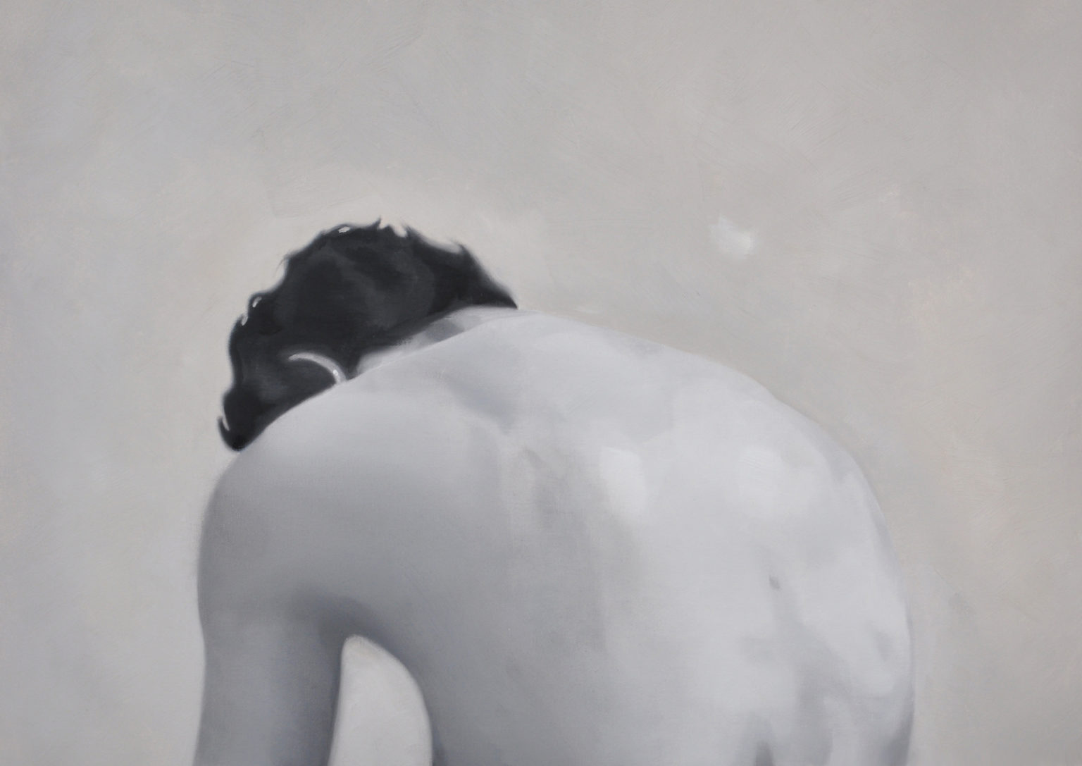 Black-and-white view of a seated figure bent forward, shown from behind.