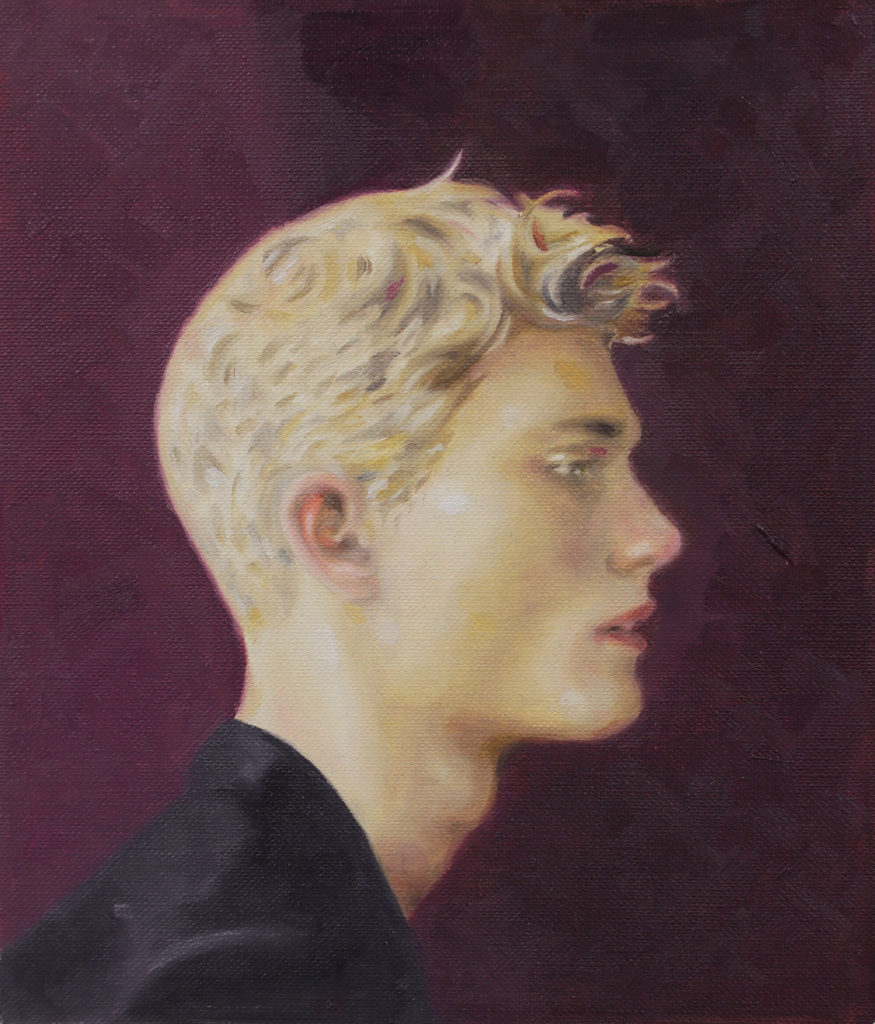 Blond young man in profile wearing a dark top against a burgundy background.