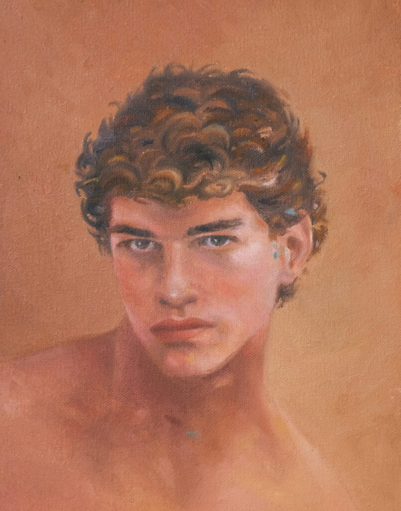 Portrait of a young man turning toward the viewer against a muted green background.