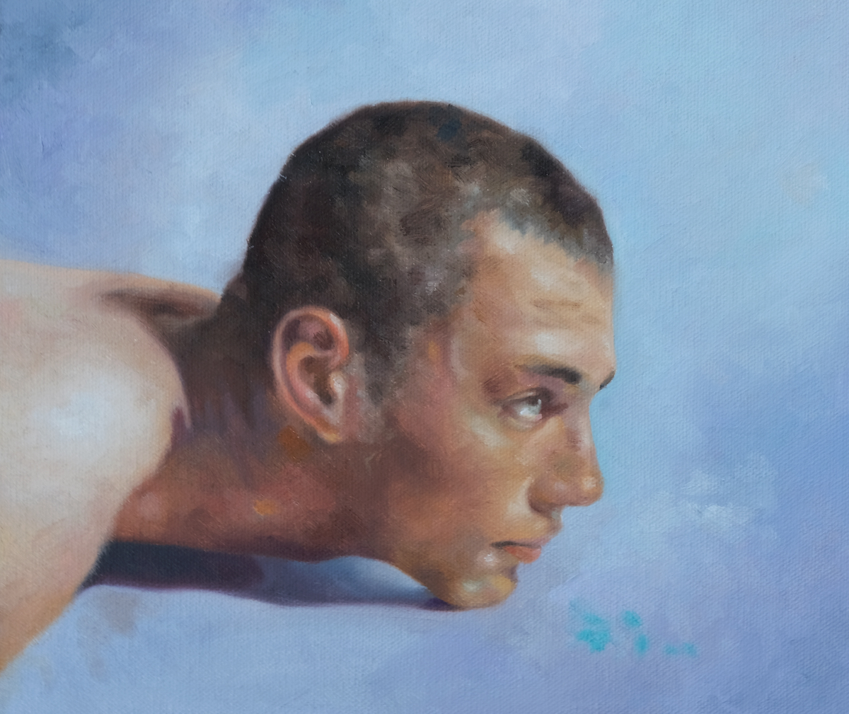 Close portrait of a young man resting on his side against a pale blue background.